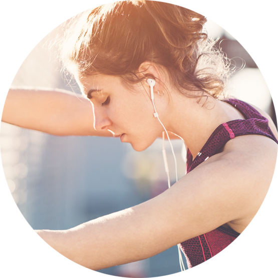 A woman in athletic gear stands outdoors, looking determined as she prepares for a run.