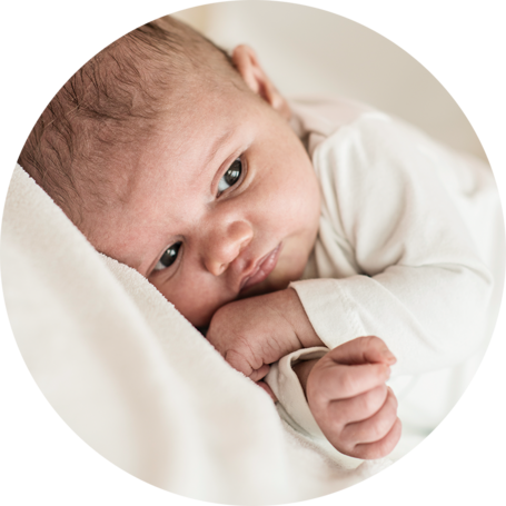 Newborn baby lying on a soft blanket, resting their head on their arm, looking calm and comfortable.